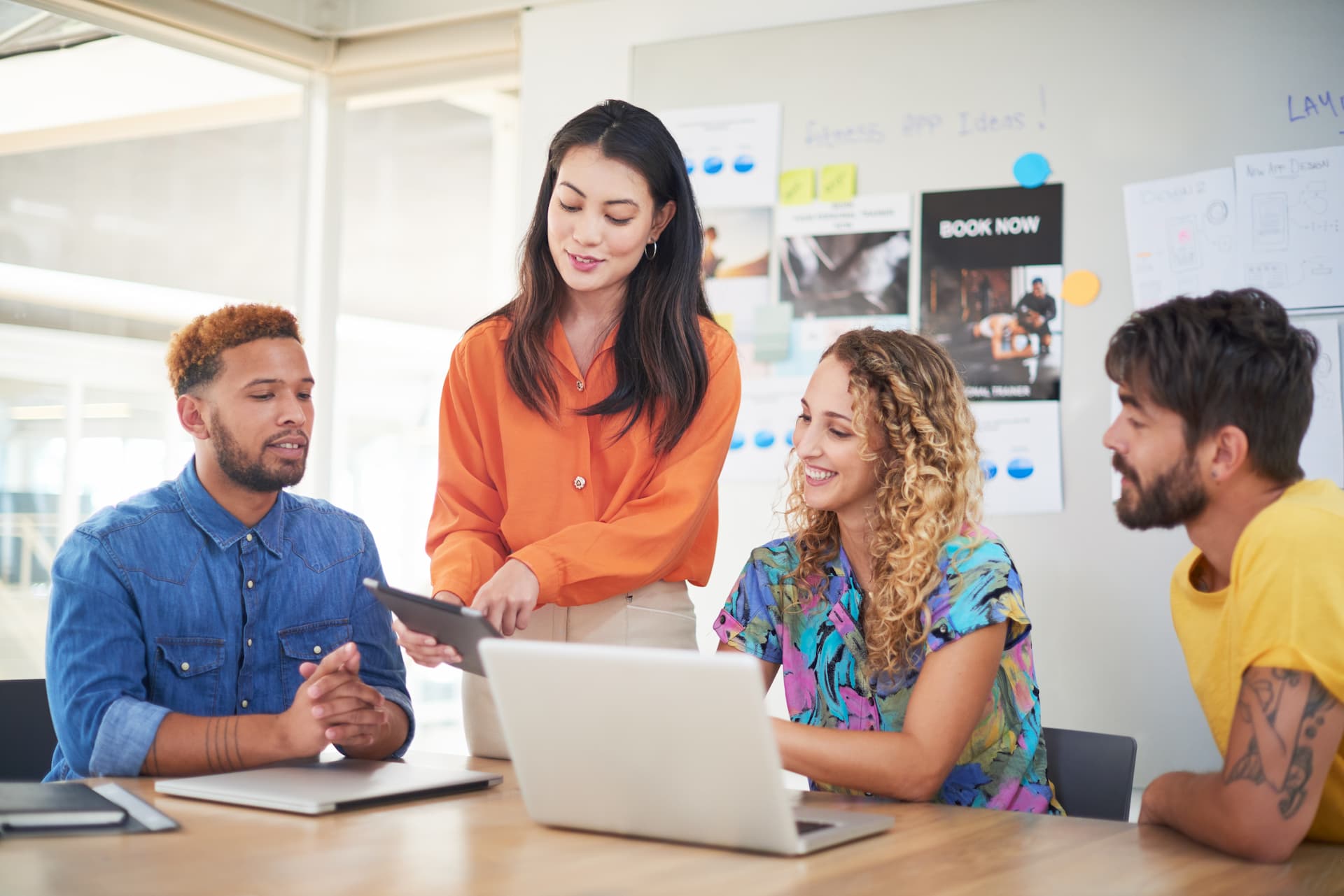 A woman stands confidently before a diverse group of individuals, engaging them with her presence and communication.